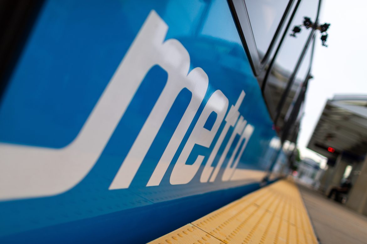 Photo of a MetroLink train at a station platform with a closeup of the Metro logo that runs along the side of the train
