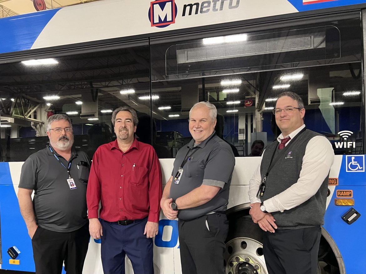 Members of the Metro Quality Assurance team pose in front of a bus