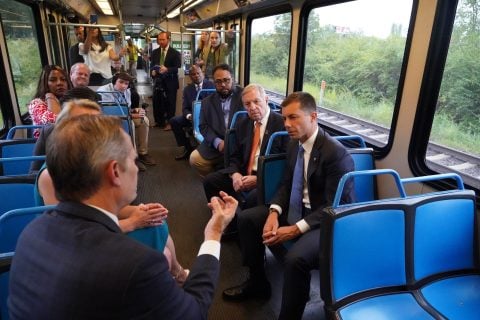 Photo of BSD President & CEO Taulby Roach on a MetroLink train speaking with U.S. Secretary of Transportation Pete Buttigieg, U.S. Senator Dick Durbin and Mayor Charles Powell III of East St. Louis